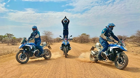 L’équipe masculine d’Inde montre les pilotes en action, où le pilote du milieu se dresse telle une chandelle sur sa moto avec les mains jointes au-dessus de sa tête.